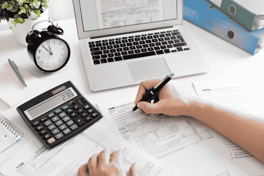 Person reviewing tax and financial paperwork with a calculator and laptop, illustrating how to read a credit card statement and spot hidden costs.