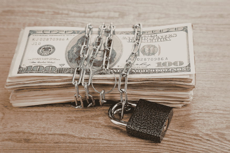Stack of US dollar bills secured with a chain and lock, representing the concept of an emergency fund in personal finance