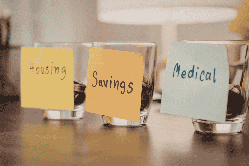 Savings jars labeled housing, savings, and medical, illustrating financial education and budgeting for emergency funds
