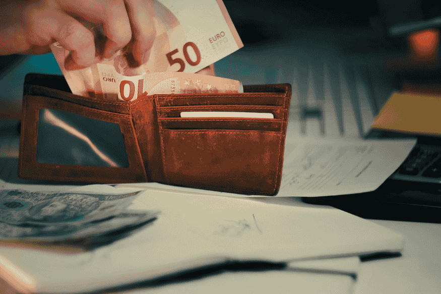 Person placing cash into a wallet, showing how personal loans provide direct access to funds
